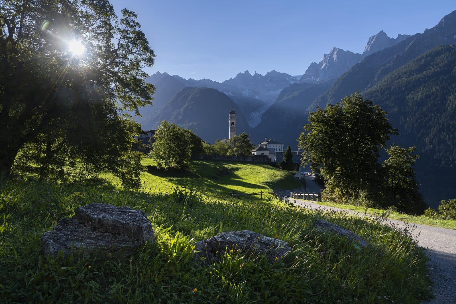 Una valle d'alta montagna con un villaggio in pietra e cime innevate