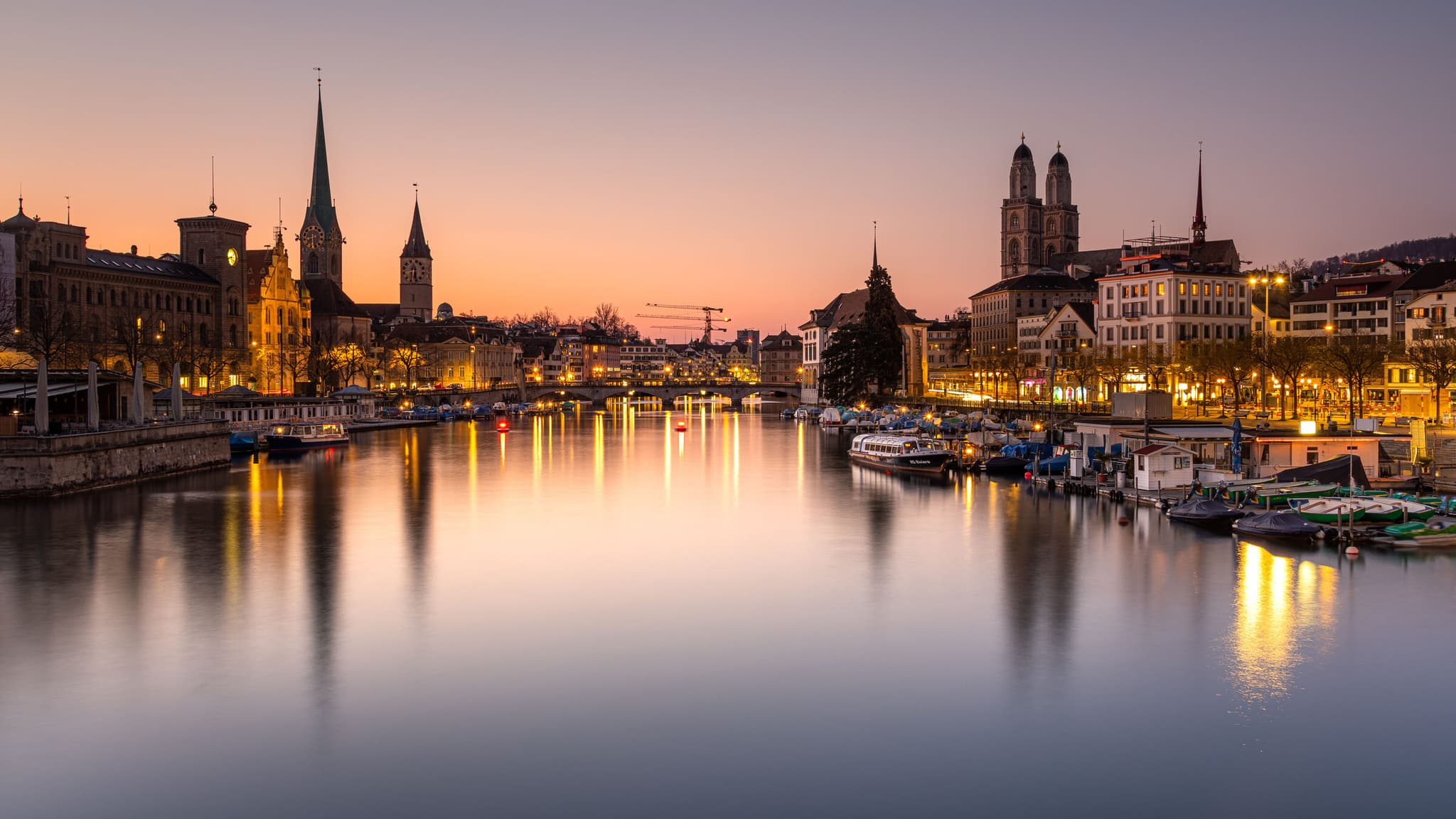 Zürcher Altstadt und die Limmat bei Sonnenuntergang, mit den Türmen von Grossmünster, Fraumünster und St. Peter.